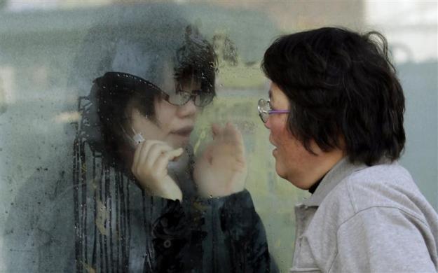 A mother tries to talk to her daughter who has been isolated for signs of radiation after evacuating from the vicinity of Fukushima's nuclear plants, at a makeshift facility to screen, cleanse and isolate people with high radiation levels in Nihonmatsu, northern Japan, after a massive earthquake and tsunami that are feared to have killed more than 10,000 people. (REUTERS)