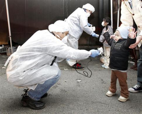 Officials in protective gear check for signs of radiation on children who are from the evacuation area near the Fukushima Daini nuclear plant in Koriyama. (REUTERS)