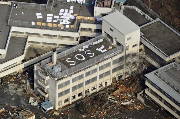 People wait to be rescued atop a building with the letters "SOS" after an earthquake in Kesennuma, Miyagi Prefecture. (REUTERS)