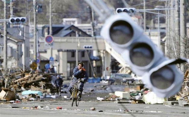 A man rides a bicycle through a debris-strewn street in Miyako, Iwate Prefecture in northeastern Japan. (REUTERS)