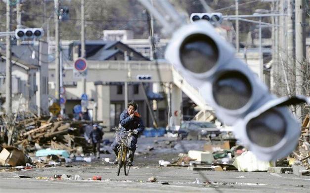 A man rides a bicycle through a debris-strewn street in Miyako, Iwate Prefecture in northeastern Japan. (REUTERS)