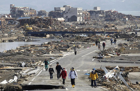 People walk a road between the rubble of destroyed buildings in Minamisanriku town, Miyagi Prefecture, northern Japan, three days after the earthquake with a magnitude of 9.0 struck. (AP)