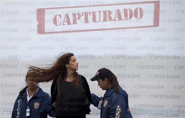 Suspected Colombian drug trafficker Gloria Rojas (C) tosses her hair as she is escorted by police officers during her extradition to the U.S. at Simon Bolivar Airport in Caracas. (REUTERS)