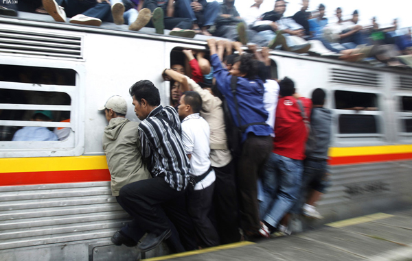 People hang onto an entrance of a commuter train which will transport them to Jakarta, in Depok, Indonesia's West Java province May 31, 2010. According to PT Kereta Api Indonesia, their trains operate 300 cars each day to serve about 500,000 commuters in Jakarta. In 2007 as many as 26 people were killed due to electricity shock and from falling off the roofs of trains. (REUTERS)