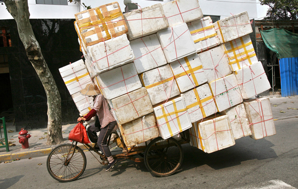A woman carries styrofoam for recycling on her bicycle in a street in Shanghai October 5, 2006. (REUTERS)