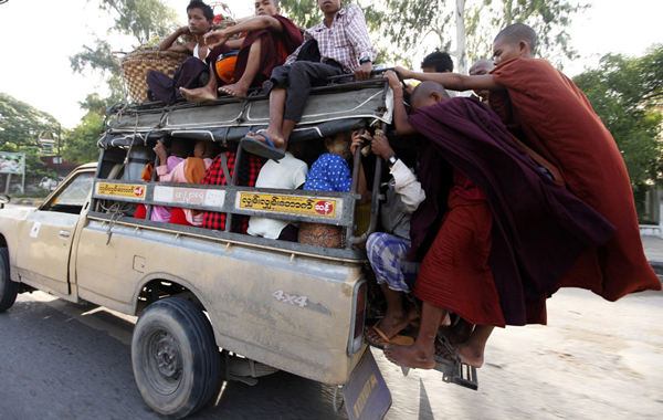 Buddhist novice monks cling on to the back of a vehicle filled with passengers in central Mandalay August 20 ,2010 .(REUTERS)