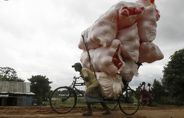 A rickshaw puller transports sacks filled with plastic balls on the outskirts of Agartala, capital of India's northeastern state of Tripura, October 9, 2010. (REUTERS)