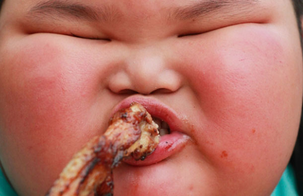 Lu Hao, who is nearly 4 years old, eats a roast chicken wing at a market in Foshan, Guangdong province. The Sun newspaper reported he is getting so big that his parents are frightened of him - and they claim the youngster throws vicious tantrums if they try to stop him from gorging on huge plates of ribs and rice. They claim that although they try to cut his meals, he has gained 21 pounds in the last year. (REUTERS)