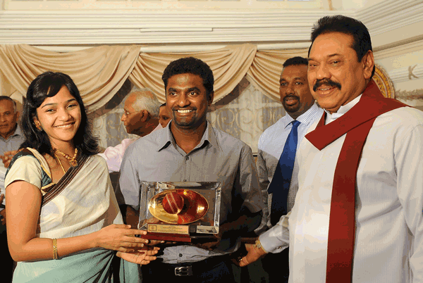 Sri Lankan president Mahinda Rajapakse (right) presents a gift to star cricketer Muttiah Muralitharan (centre) flanked by his wife Madhi Malar during a tea party at the official Presidential residency in Colombo on Monday. (AFP)