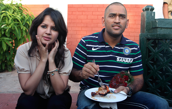 Indian cricket team Mahendra Singh Dhoni, right, eats, with his wife Sakshi Singh Rawat at left, during a tea party at the governor's house in Mumbai, India. (AFP)