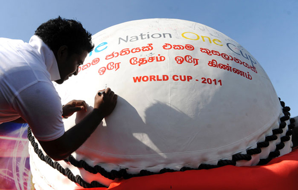 Sri Lankan fans autograph a giant replica cricket ball at a promotional event in Colombo. (AFP)