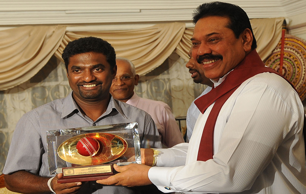 Sri Lankan President Mahinda Rajapakse (R) presents a souvenir to star cricketer Muttiah Muralitharan during a tea party at the official Presidential residency in Colombo. (AFP)