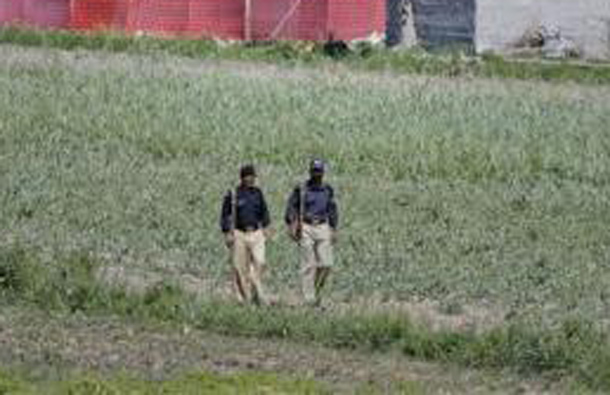 Pakistani policemen walk past a compound, surrounded in red fabric, where locals reported a firefight took place overnight in Abbotabad, located in Pakistan's Khyber Pakhtunkhwa province, May 2, 2011. (REUTERS)