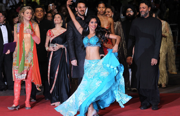 A dancer dances as Indian director Jeff Zimbalist (C back) and Indian director Rakeysh Omprakash Mehra (R) arrive on the red carpet before the screening of "Bollywood - The Greatest Love Story Ever Told" presented out-of-cometition at the 64th Cannes Film Festival on May 14, 2011 in Cannes. (AFP)