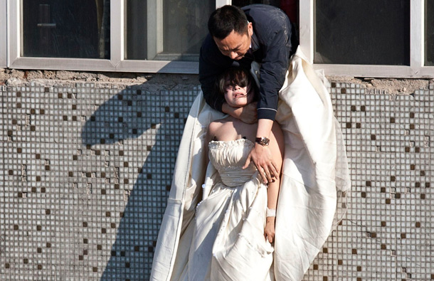 A 22-year-old woman in a wedding gown is grabbed by Guo Zhongfan, a local community officer, as she attempts to kill herself by jumping out of a seven-storey residential building in Changchun, Jilin province. (REUTERS)