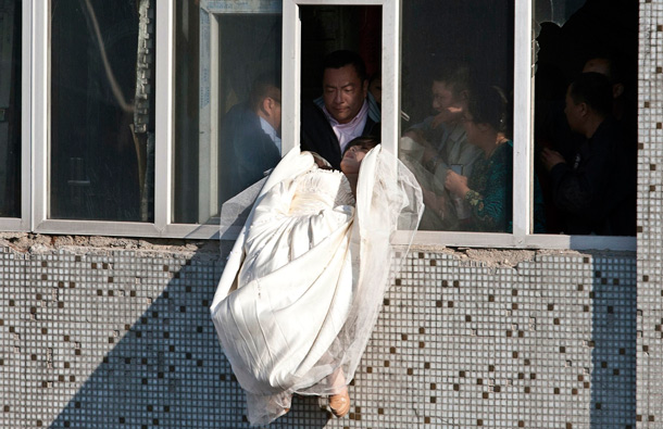 A 22-year-old woman in wedding gown is grabbed by Guo Zhongfan, a local community officer, as she attempts to kill herself by jumping out of a seven-storey residential building in Changchun, Jilin province. (REUTERS)