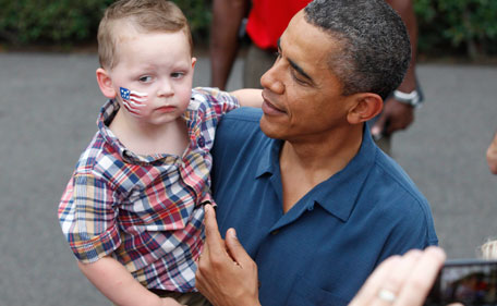 President Barack Obama picks up a child as he greets military families at an Independence Day celebration on the South Lawn of the White House in Washington, Monday, July 4, 2011. (AP)