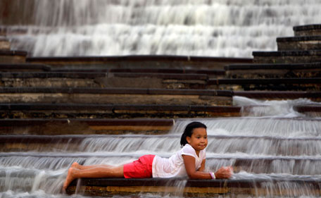 Tayahna Heard, 6, of Godfrey, Ill., cools off in a fountain as she waits to watch a fireworks show Monday, July 4, 2011, in St. Louis. (AP)