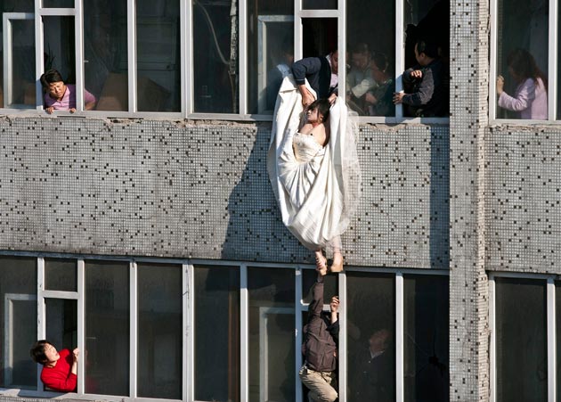 22-year-old woman in a wedding gown is grabbed by Guo Zhongfan, a local community officer, as she attempts to kill herself by jumping out of a seven-storey residential building in Changchun, Jilin province. (REUTERS)