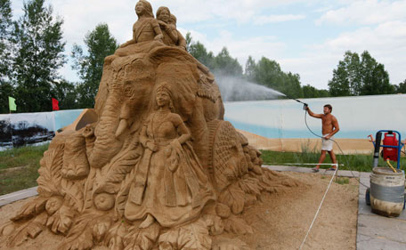 A park employee sprays a sand sculpture with glutinous solution at a park in Russia's Siberian city of Krasnoyarsk, July 6, 2011. Nine professional and amateur artists took part in a contest to build sand sculptures under the general theme of "The Carnival" and created works interpreting mythological plots, fairy-tales and cartoons.  (REUTERS)