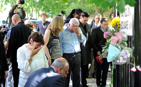 Amy Winehouse's father Mitch Winehouse (C) mother Janis Winehouse (C,L) brother Alex Winehouse (R) and former boyfriend Reg Traviss (2nd R) look at floral tributes left at her house by fans on July 25, 2011 in London, England.  (GETTY)