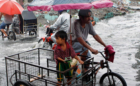 People travel in a flooded street in Las Pinas, Metro Manila July 26, 2011. More than 100,000 families were displaced due to flooding, while 11 fishermen were missing in central Philippines as Typhoon Juaning battered the main Luzon island, forcing schools to close and grounding domestic flights and ferry services, disaster officials said on Tuesday.  (REUTERS)