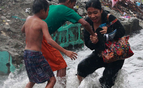 Children help a woman make her way through a flooded street in Las Pinas, Metro Manila July 26, 2011. More than 100,000 families were displaced due to flooding, while 11 fishermen were missing in central Philippines as Typhoon Juaning battered the main Luzon island, forcing schools to close and grounding domestic flights and ferry services, disaster officials said on Tuesday.  (REUTERS)