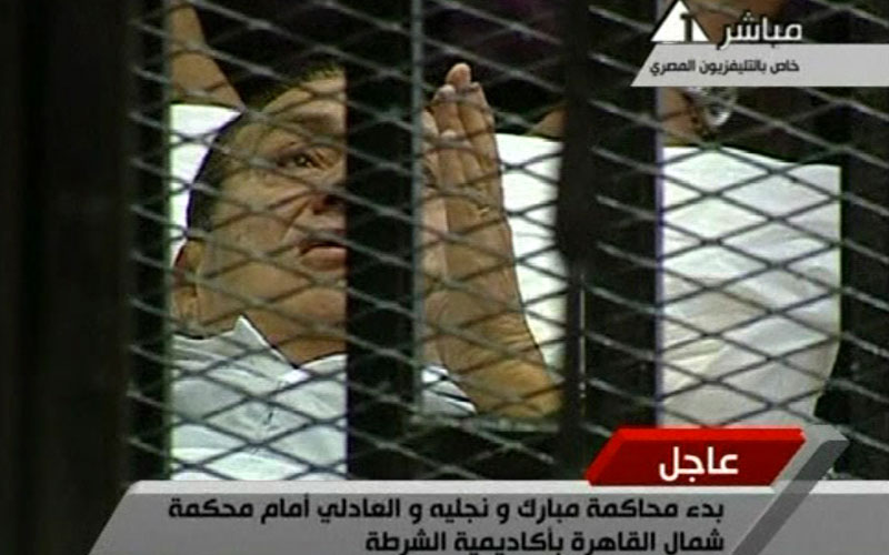 This video image taken from Egyptian State Television shows 83-year-old Hosni Mubarak laying on a hospital bed inside a cage of mesh and iron bars in a Cairo courtroom as his historic trial began on charges of corruption and ordering the killing of protesters during the uprising that ousted him. The scene, shown live on Egypt's state TV, was Egyptians' first look at their former president since Feb. 10, the day before his fall when he gave a defiant speech refusing to resign. (AP)
