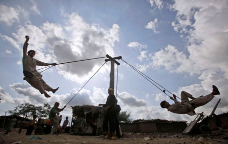 Pakistani boys play on a homemade swing during the holy month of Ramadan, in a slum on the outskirts of Islamabad, Pakistan, Saturday, Aug. 13, 2011, on the eve of country's Independence Day. (AP)