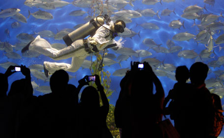 Visitors take pictures of a professional diver wearing an Elvis Presley attire as he swims at an aquarium inside the Ocean Park in Manila August 15, 2011. Presley, the "King of Rock and Roll", died at his home, Graceland Mansion, in Memphis, Tennessee, at the age of 42 on August 16, 1977 from drug overdose. (REUTERS)