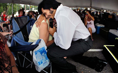 Elvis tribute artist Marcos Santos gives a personal serenade to Louise Smith of Southaven, Miss., during a performance in the Graceland Entertainment Pavilion in Memphis, Tenn. before a vigil marking the 34th anniversary of the death of Elvis Presley Monday night, Aug 15, 2011. (AP)