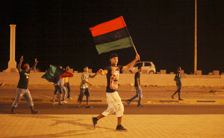 Men walk on a street carrying a pre-Gaddafi's flag during the celebrations of the capture in Tripoli of his son and one-time heir apparent, Seif al-Islam, at the rebel-held town of Benghazi, Libya, early Monday, Aug 22, 2011. Libyan rebels raced into Tripoli in a lightning advance Sunday that met little resistance as Moammar Gaddafi's defenders melted away and his 40-year rule appeared to rapidly crumble. (AP)