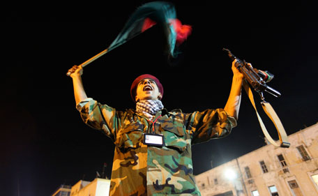 A man holds a weapon and a Kingdom of Libya flag as people gather near the courthouse in Benghazi August 22, 2011 to celebrate the entry of rebel fighters into Tripoli. Jubilant rebel fighters streamed into the heart of Tripoli as Moammar Gaddafi's forces collapsed and crowds took to the streets to celebrate, tearing down posters of the Libyan leader. (REUTERS)