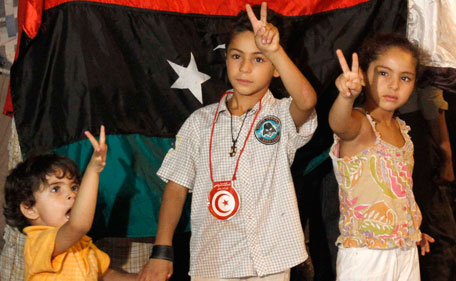 Young members of the Libyan community in Tunisia gesture outside the Libyan Embassy in Tunis August 22, 2011 as others gather to celebrate the entry of rebel fighters into Tripoli. Jubilant rebel fighters streamed into the heart of Tripoli as Moammar Gaddafi's forces collapsed and crowds took to the streets to celebrate, tearing down posters of the Libyan leader. (REUTERS))