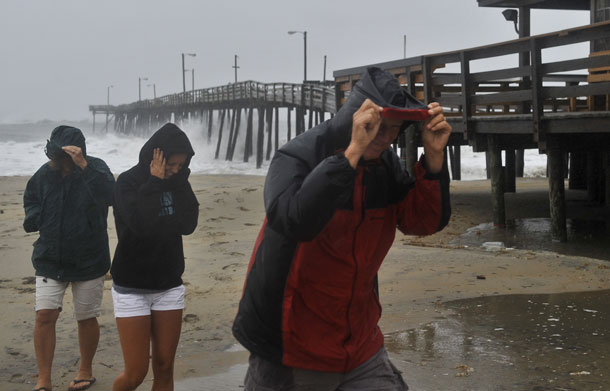 A family protect themselves from the wind and rain as they return to their car at Nags Head Fishing Pier in Nags Head in the Outer Banks of North Carolina on August 27, 2011 as Hurricane Irene pounded the coast of North Carolina. Hurricane Irene clobbered the US east coast Saturday, killing at least three people and paralyzing air traffic before barreling north on course for a rare direct hit on New York City. (AFP)