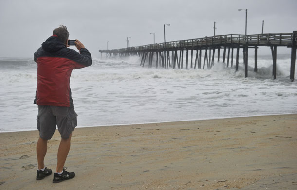 A man photographs huge waves pound Nags Head Fishing Pier in Nags Head in the Outer Banks of North Carolina on August 27, 2011 as Hurricane Irene pounded the coast of North Carolina. Packing winds of 85 miles (140 kilometers) an hour, Irene was a weakened but still massive category one storm when it made landfall at 8:00 am (1200 GMT) at Cape Lookout, North Carolina, near a chain of barrier islands. (AFP)