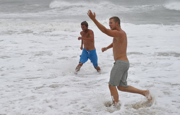 Two men enjoy the rough surf at the beach in Nags Head in the Outer Banks of North Carolina on August 27, 2011 as Hurricane Irene pounded the coast of North Carolina. Hurricane Irene clobbered the US east coast Saturday, killing at least three people and paralyzing air traffic before barreling north on course for a rare direct hit on New York City. (AFP)
