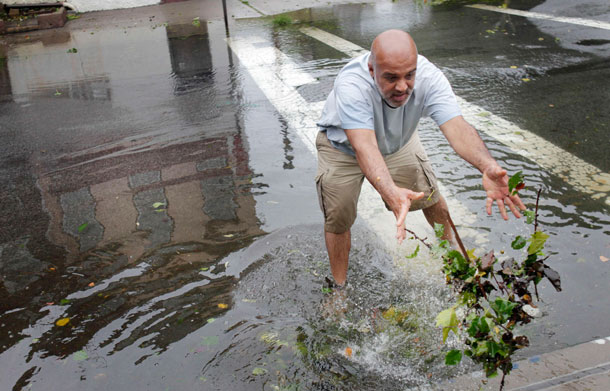 Yeshwant Chitalkar clears a drain in the street of debris with his hands in Brooklyn, New York, Sunday, Aug. 28, 2011.  Seawater surged into the streets of Manhattan on Sunday as Tropical Storm Irene slammed into New York, downgraded from a hurricane but still unleashing furious wind and rain. The flooding threatened Wall Street and the heart of the global financial network.  (AP)
