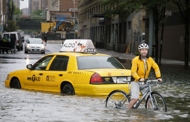 A bicyclist makes his way past a stranded taxi on a flooded New York City Street as Tropical Storm Irene passes through the city, Sunday, Aug. 28, 2011. Although downgraded from a hurricane to a tropical storm, Irene's torrential rain coupled with high winds and tides worked in concert to flood parts of the city. (AP)