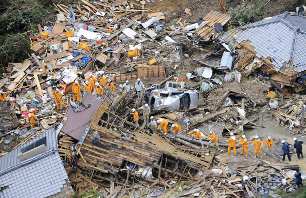 Volunteer firefighters search destroyed houses for missing people after heavy downpours by Typhoon Talas caused a landslide at Tanabe, central Japan. The storm dumped record amounts of rain Sunday in western and central Japan as it turned towns into lakes, washed away cars and triggered mudslides that obliterated houses. (AP)