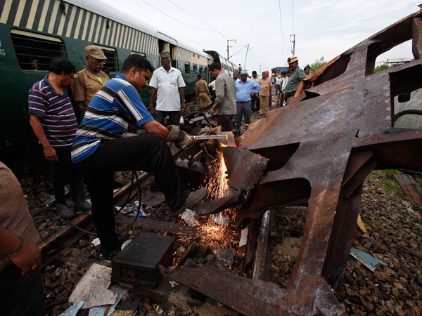 Rescuers work to remove the wreckage of a derailed train compartment after two trains collided near Arakkonam, southwest of Chennai, India, Wednesday, Sept. 14, 2011. The passenger train traveling through southern India collided with another train stopped at a signal on Tuesday, killing eight people and injuring dozens more, a government official said. (AP)