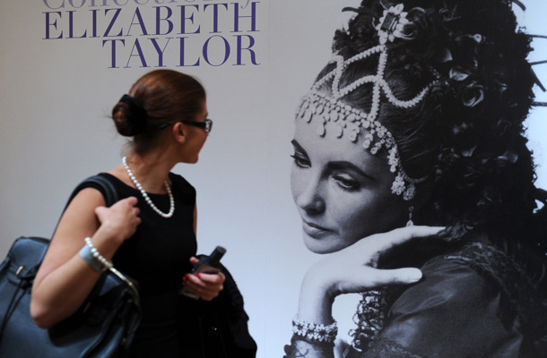 A woman looks at a poster of Elizabeth Taylor's jewelry public exhibition  in GUM on Moscow's Red Square, shortly after the exhibition opening. Christie&lsquo;s have revealed the main lots of  the Oscar-winning actress jewels to be auctioned in New York this December. (AFP)