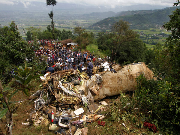 Nepalese rescue workers and civilians gather around the wreckage of a Beechcraft 1900D operated by Buddha Air after it crashed in the mountains outside Bisankunarayan village, just south of Katmandu, Nepal, early Sunday, Sept. 25, 2011. The plane carrying tourists to view Mount Everest crashed while attempting to land in dense fog on Sunday, killing all 19 people on board, officials said. (AP)