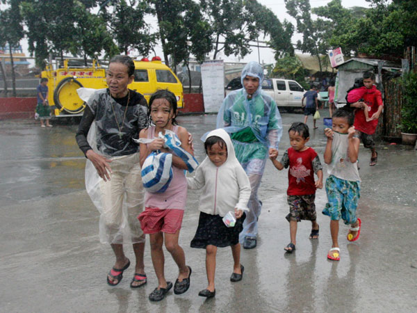 A family living near the sea front carry their belongings as they evacuate from floodwaters brought by Typhoon Nesat, locally known as Pedring, in Tondo city, metro Manila September 27, 2011. (REUTERS)