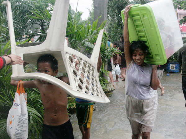 A family living near the sea front carry their belongings as they evacuate from floodwaters brought by Typhoon Nesat, locally known as Pedring, in Tondo city, metro Manila September 27, 2011. (REUTERS)