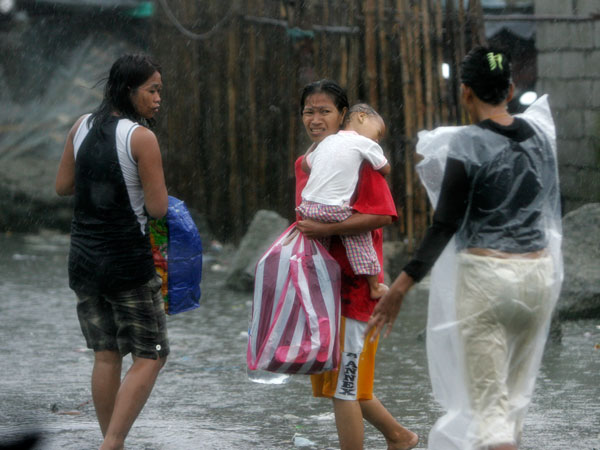A mother cuddles her baby as they evacuate from their flooded home at the height of typhoon Nesat Tuesday Sept. 27, 2011 in Manila, Philippines. (AP)