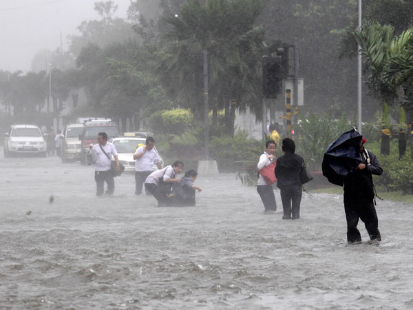 Commuters wade through the flooded boulevard at the height of typhoon Nesat Tuesday Sept. 27, 2011 in Manila, Philippines. (AP)
