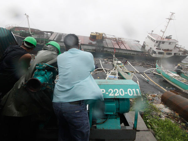 Construction workers stand near a cargo ship wash washed ashore at the sea port in Navotas city, north of Manila September 27, 2011, after Typhoon Nesat, locally known as Pedring, hit the capital, Manila. (REUTERS)