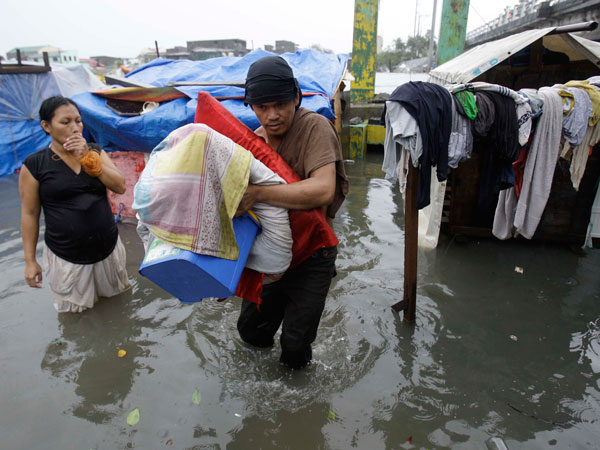 Residents living beside a river save their belongings as they evacuate to higher grounds in Navotas, north of Manila, Philippines Tuesday Sept. 27, 2011 as Typhoon Nesat hits the country. Massive flooding hit the Philippine capital on Tuesday. (AP)