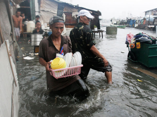 Residents living near the sea front carry their belongings as they evacuate from floodwaters brought by Typhoon Nesat, locally known as Pedring, in Tondo city, metro Manila September 27, 2011. (REUTERS)